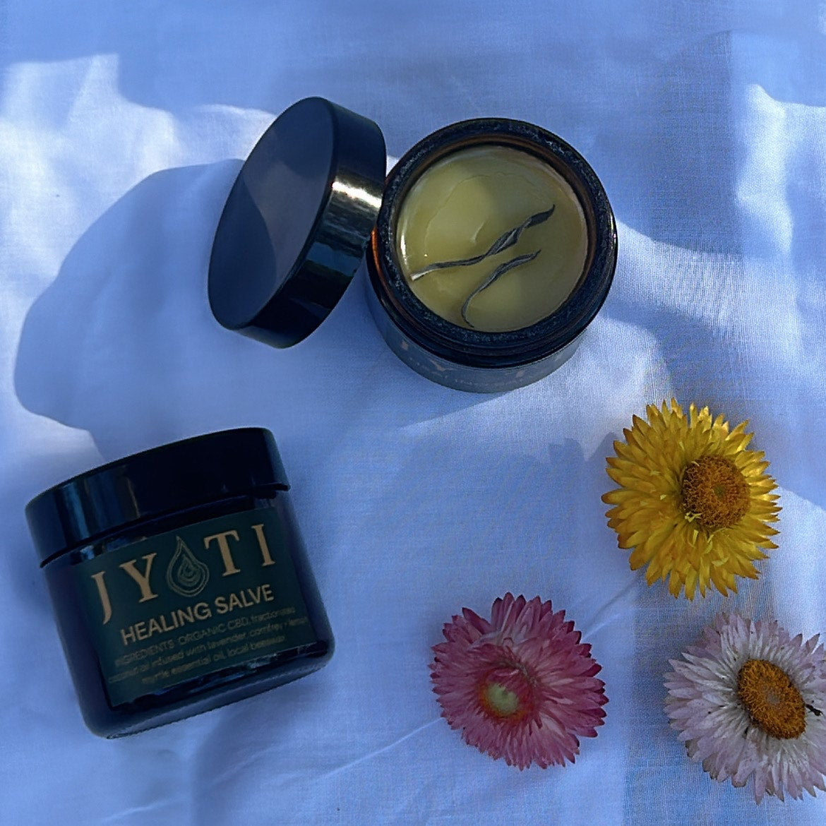 JYOTI CBD Balm showing smooth texture and vibrant natural colour on a natural material cloth 